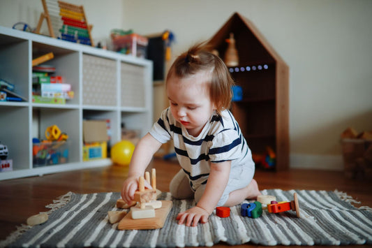 Toddler playing with wooden educational toys on a play mat, Montessori-style learning activity in a calm indoor playroom